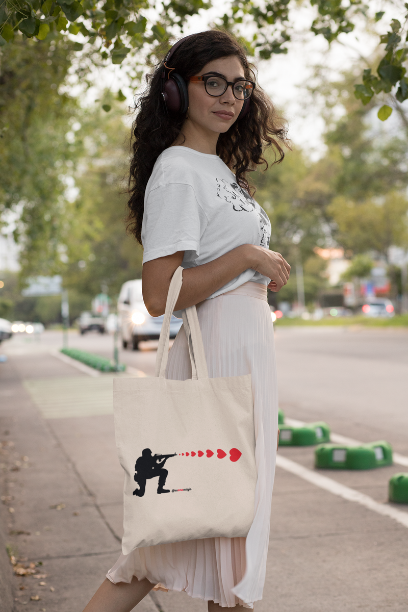 ECOBAG SOLDIER OF LOVE - Categoria BOLSAS ECOBAG - Bolsa retornável - Ecológica - Coleções Eu Amo Eu Loja  - Coleção Faça Amor. Não Faça Guerra. @euamoeu.loja - Estampa Exclusiva Eu Amo Eu - Design By Vaz (foto moça usando uma ecobag Eu Amo Eu )