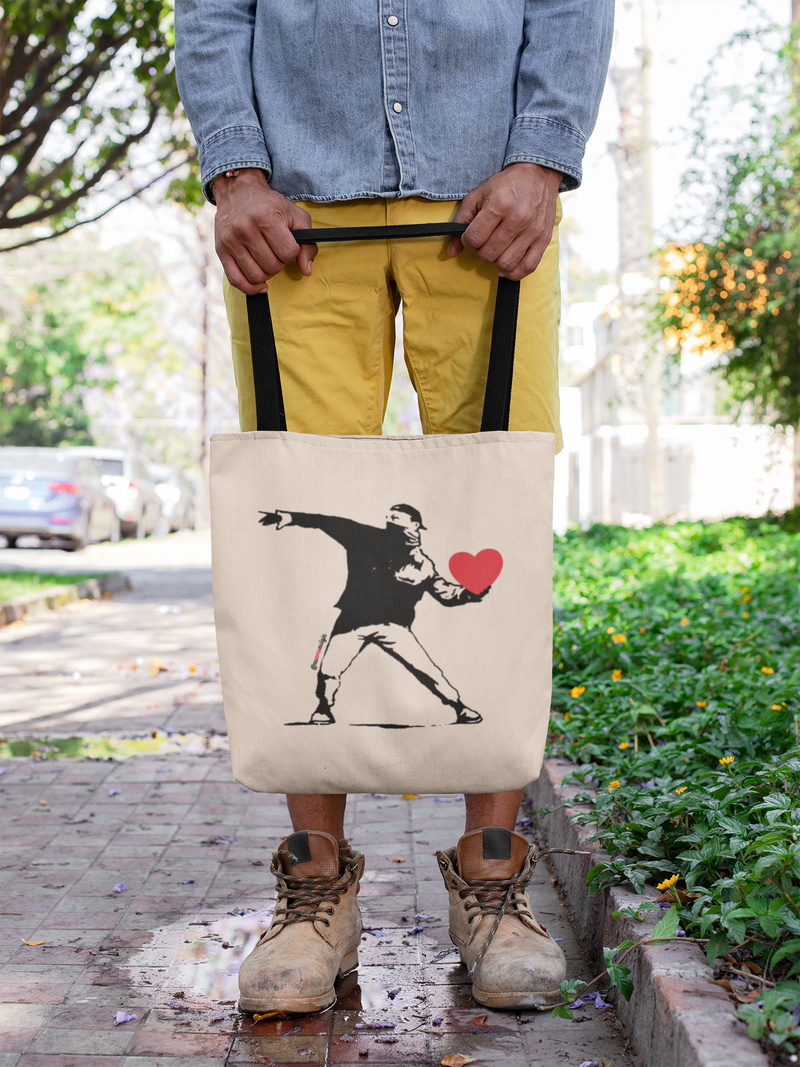 ECOBAG THE HEART SHOOTER - Categoria BOLSAS ECOBAG - Bolsa retornável - Ecológica - Coleções Eu Amo Eu Loja  - Coleção Faça Amor. Não Faça Guerra. @euamoeu.loja - Estampa Exclusiva Eu Amo Eu - Design By Vaz (foto rapaz usando uma ecobag Eu Amo Eu )