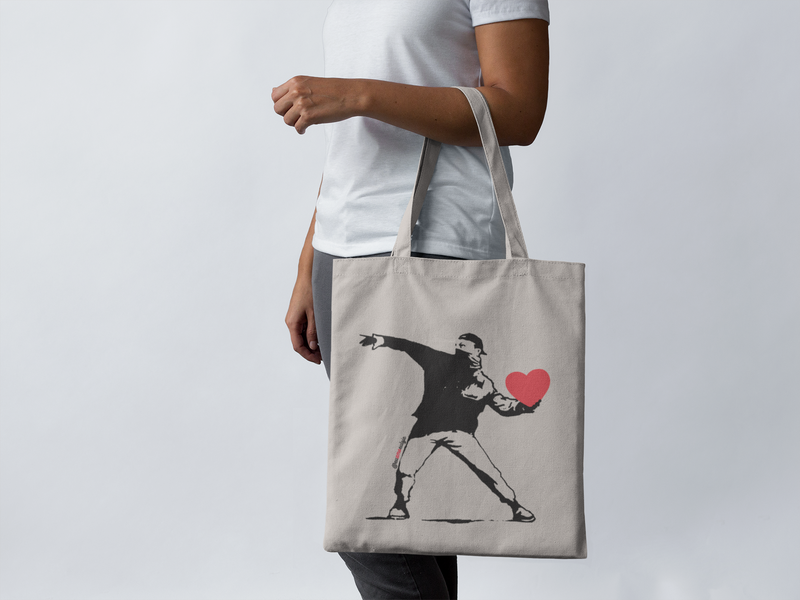 ECOBAG THE HEART SHOOTER - Categoria BOLSAS ECOBAG - Bolsa retornável - Ecológica - Coleções Eu Amo Eu Loja  - Coleção Faça Amor. Não Faça Guerra. @euamoeu.loja - Estampa Exclusiva Eu Amo Eu - Design By Vaz (foto moça usando uma ecobag Eu Amo Eu )